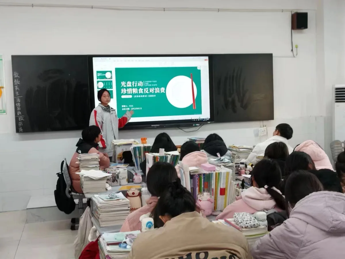 徐淑颖站在教室前给学生讲解珍惜粮食的主题